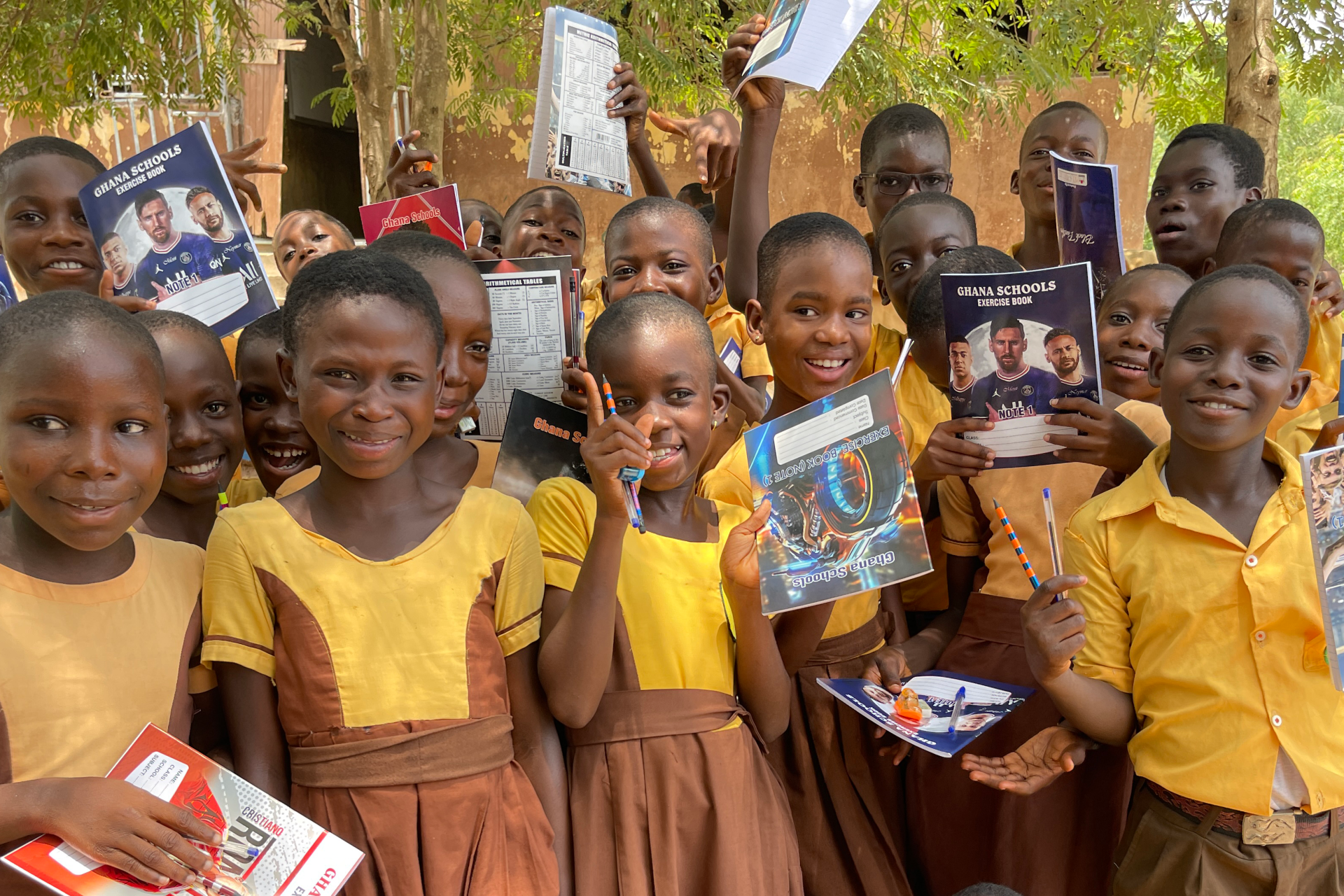 Schoolchildren in Ghana holding exercise books donated by the Fifiawoto Foundation